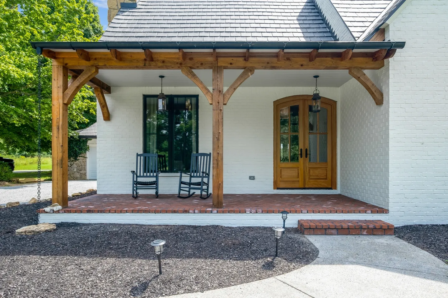 A porch with two rocking chairs and a bench.