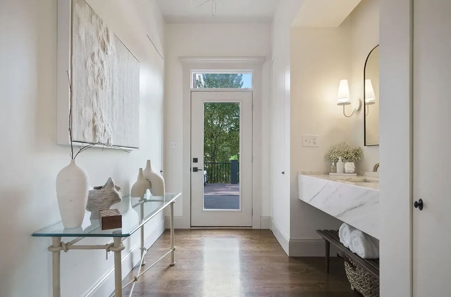 A hallway with a glass table and marble counter.