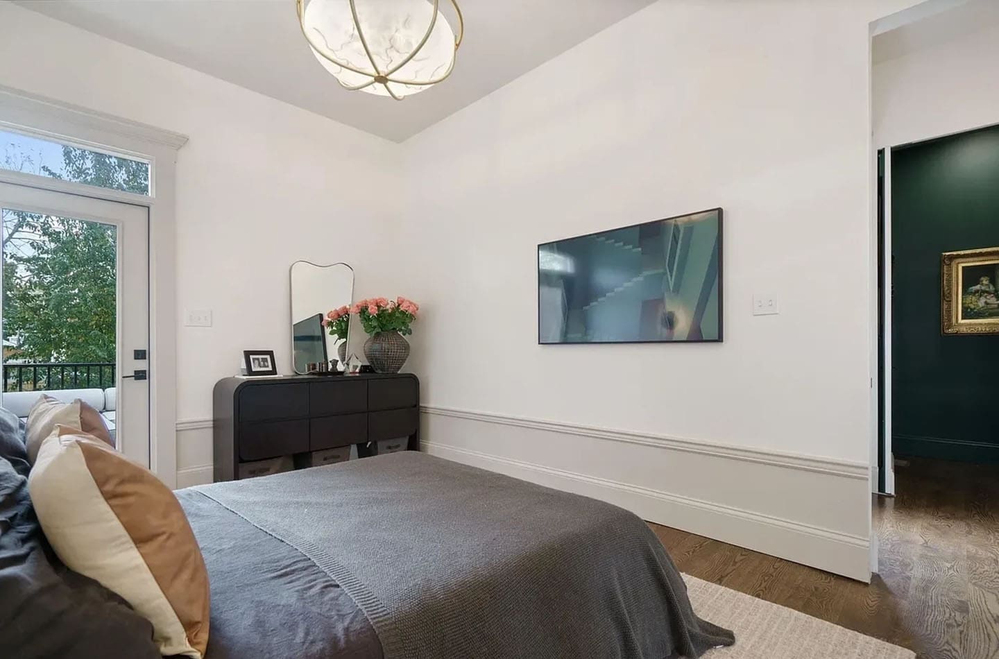 A bedroom with a bed, dresser and television.