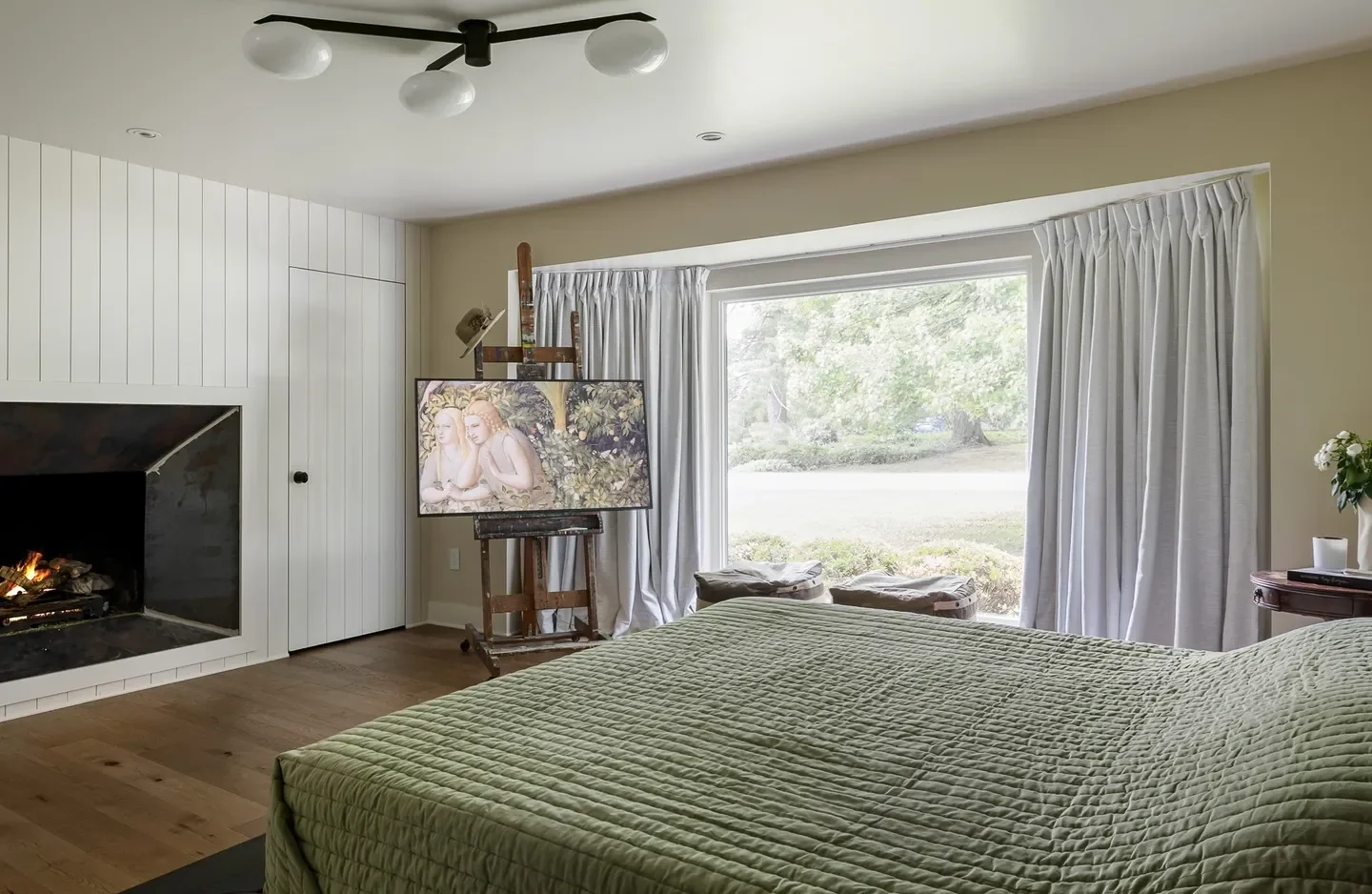 A bedroom with a bed, television and window.