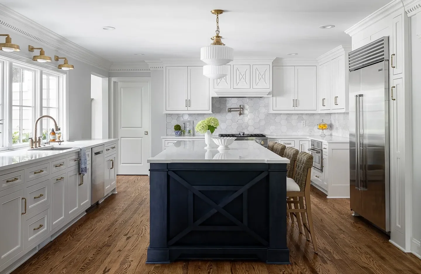 A kitchen with white cabinets and wood floors.