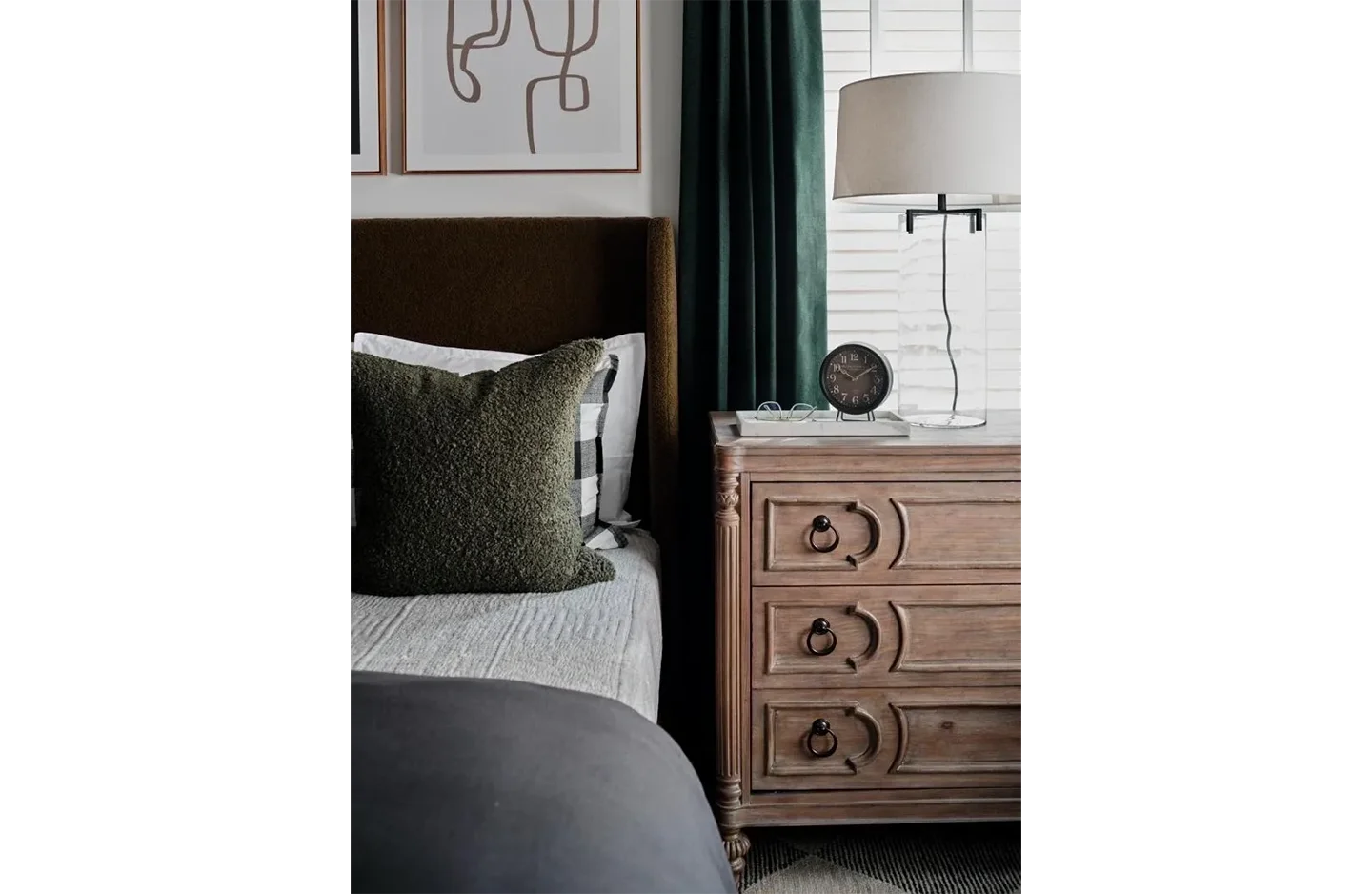 A bedroom with a bed, nightstand and lamp.