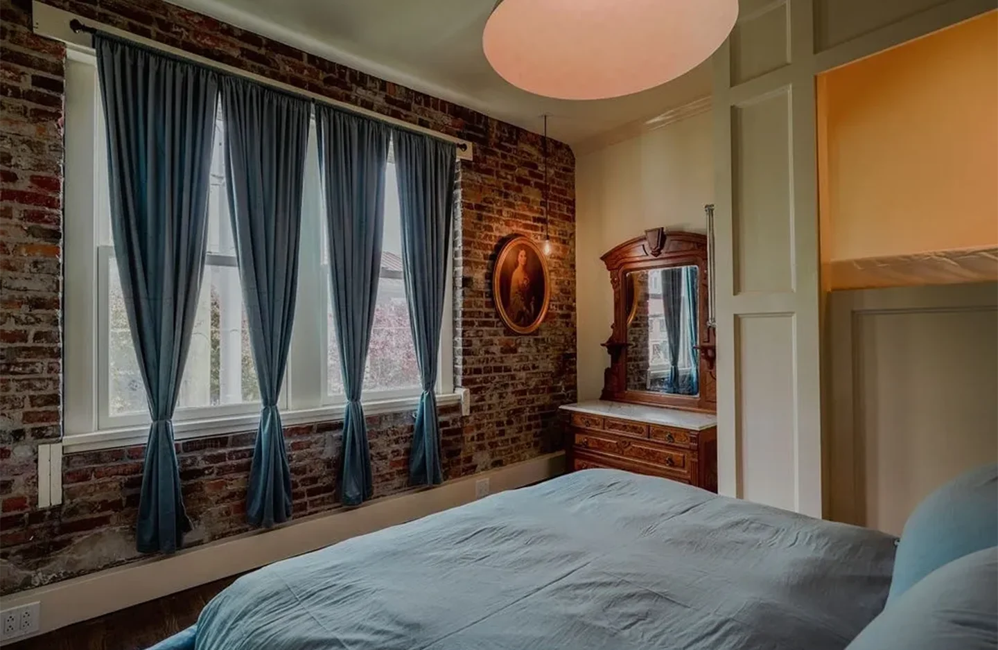 A bedroom with a bed, dresser and window.