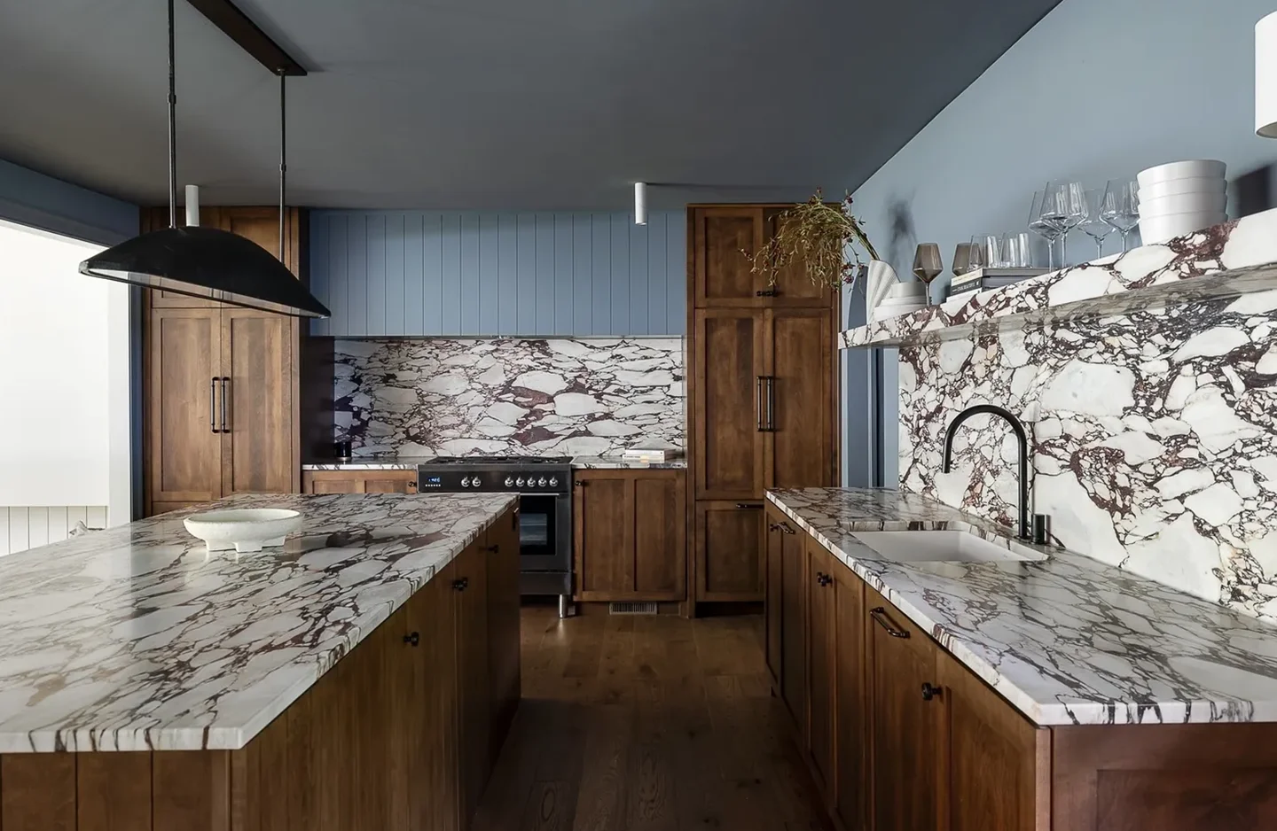 A kitchen with marble counter tops and wooden cabinets.