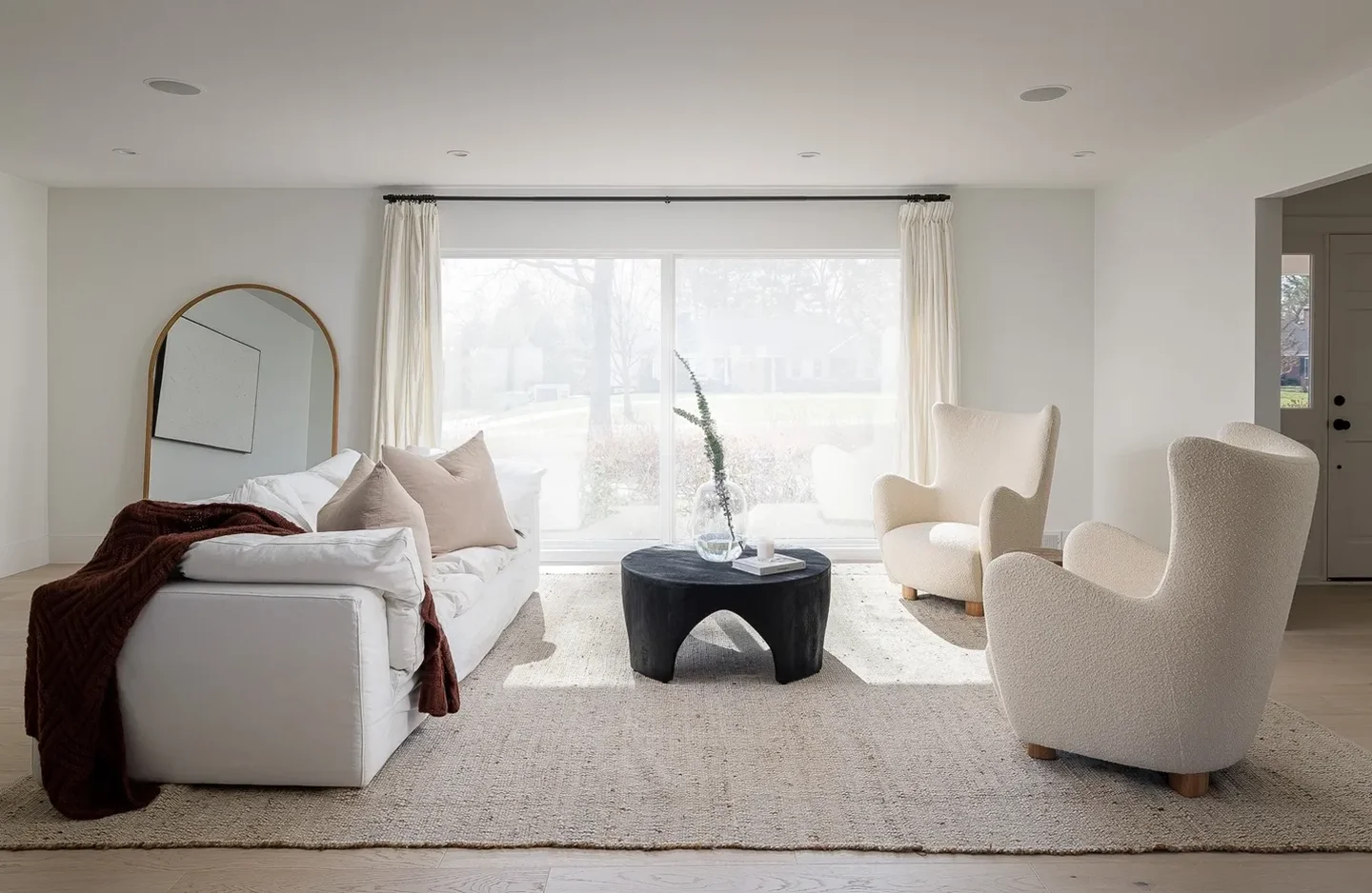 A living room with white furniture and a large window.