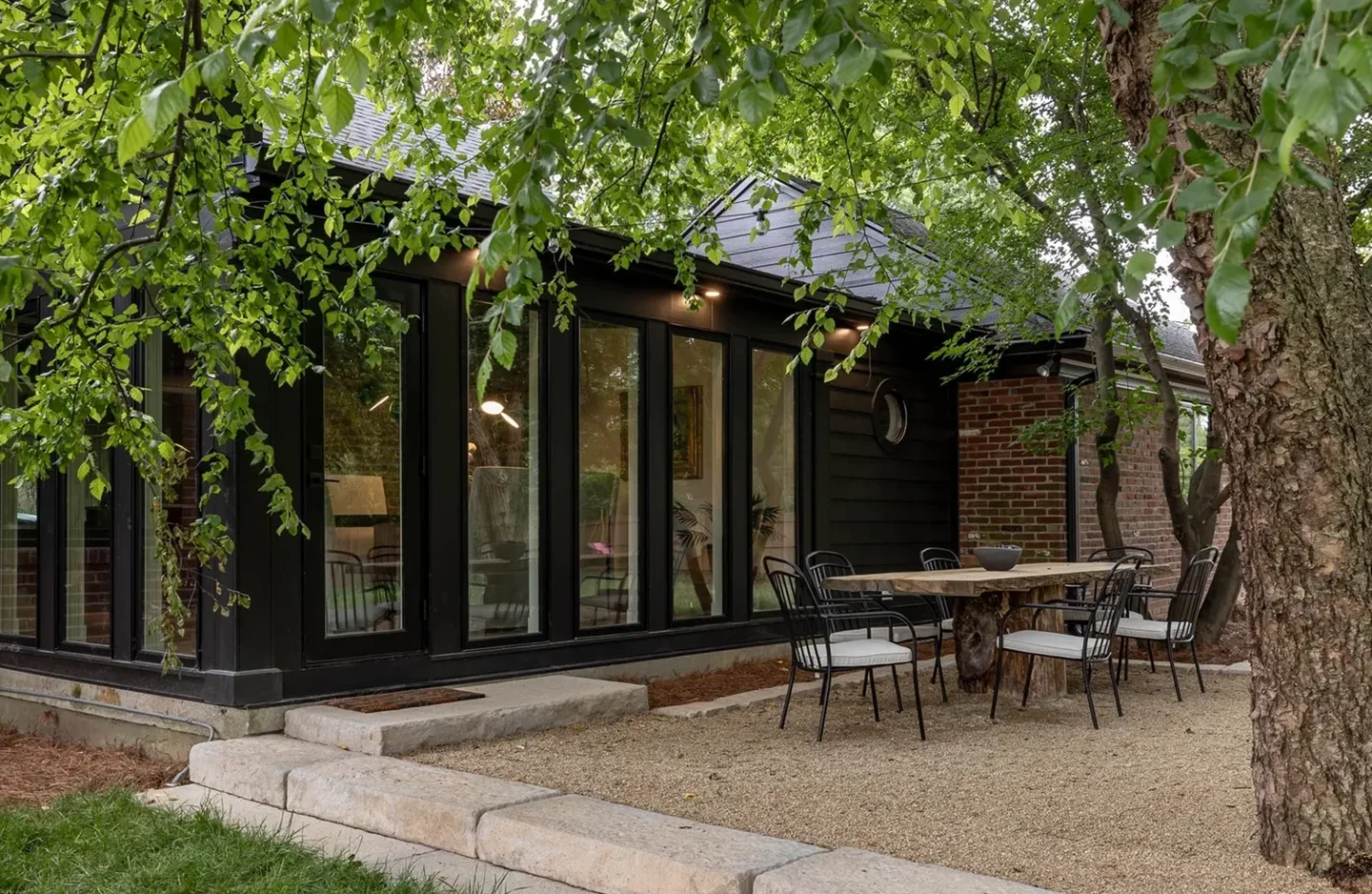 A patio with tables and chairs outside of the house.