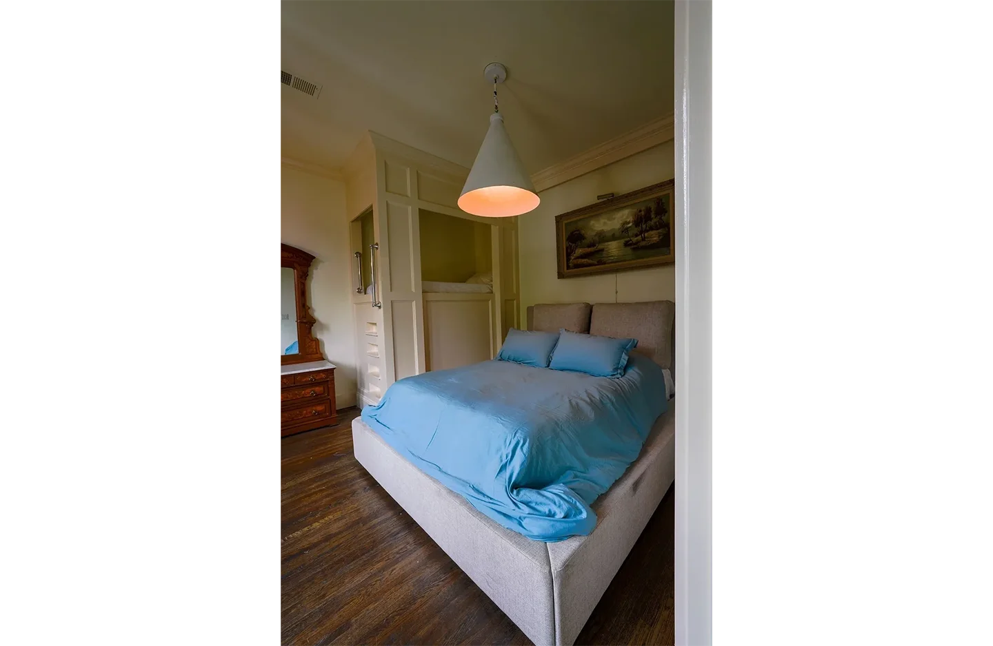 A bed room with a blue bedspread and white sheets