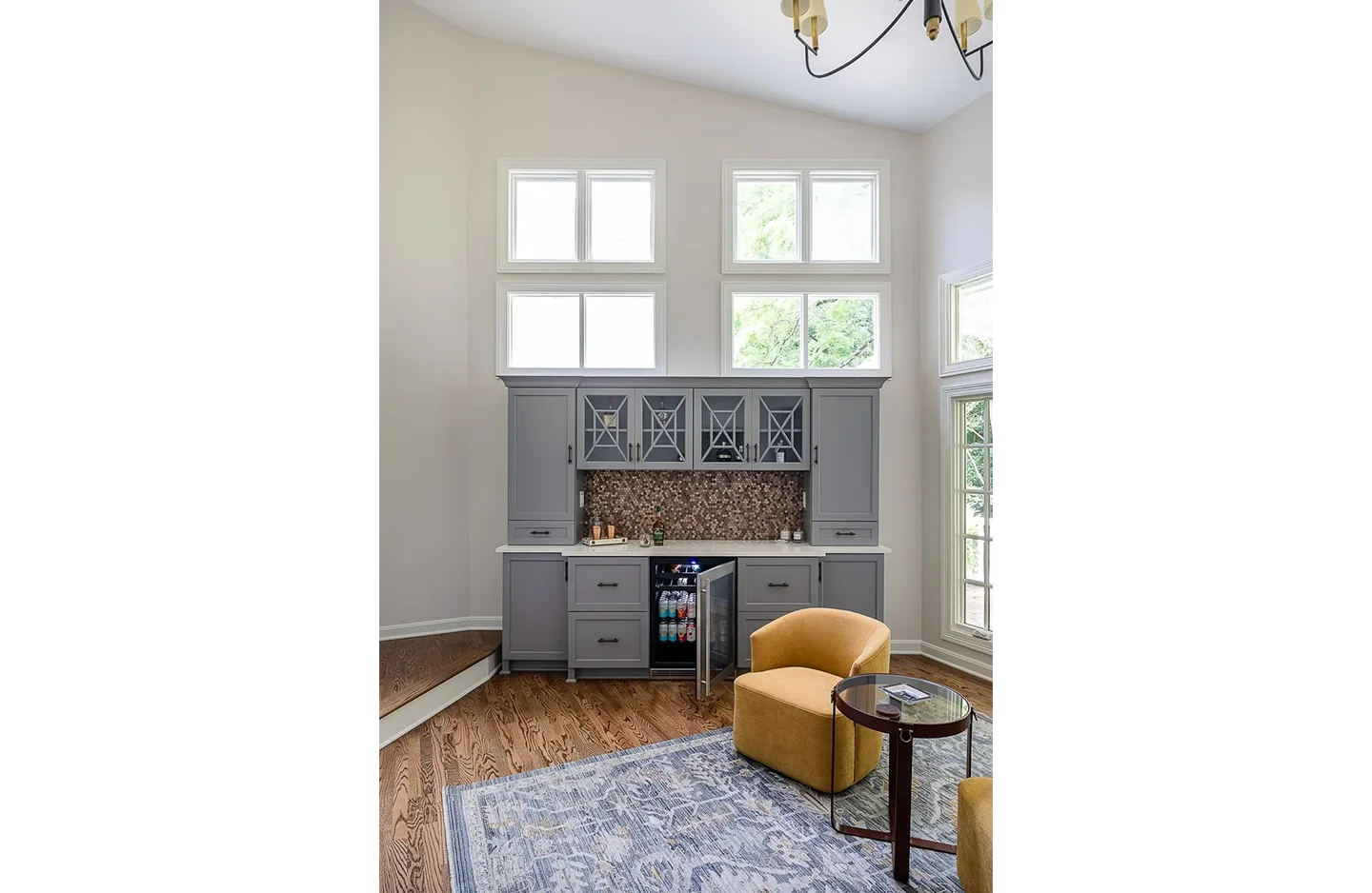 A living room with a yellow chair and a blue rug