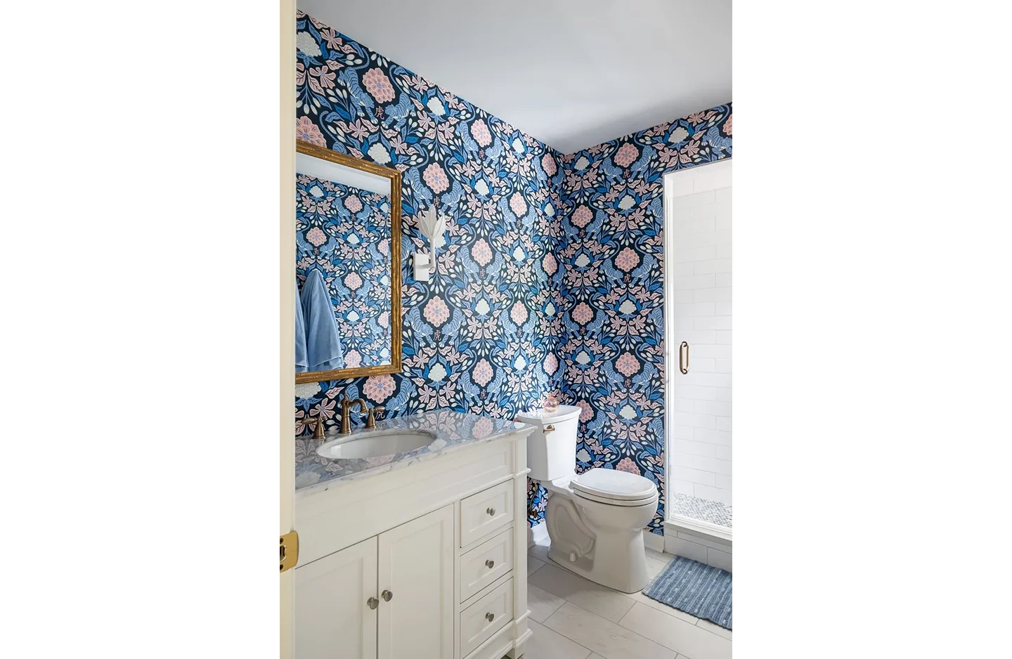 A bathroom with blue and white floral wallpaper.