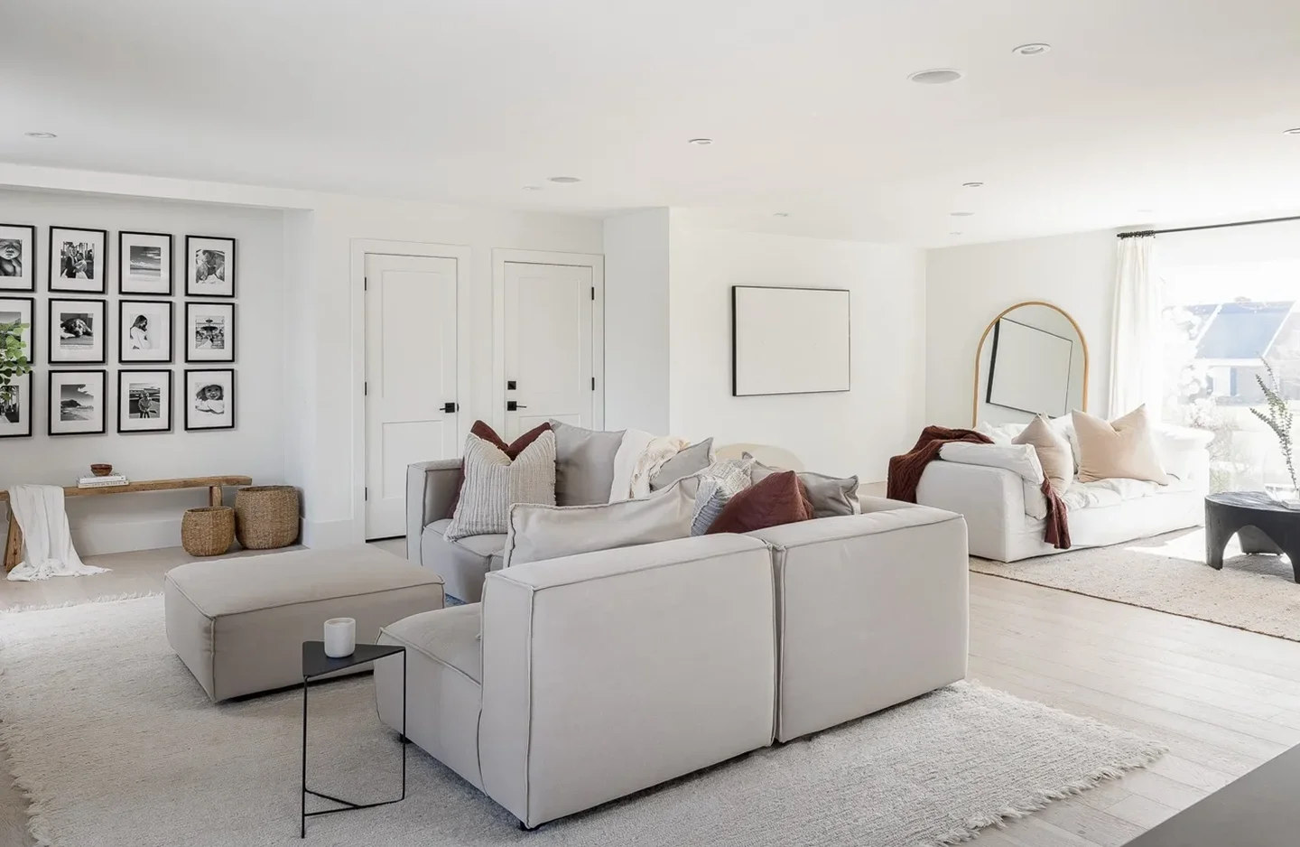 A living room with white furniture and a mirror.