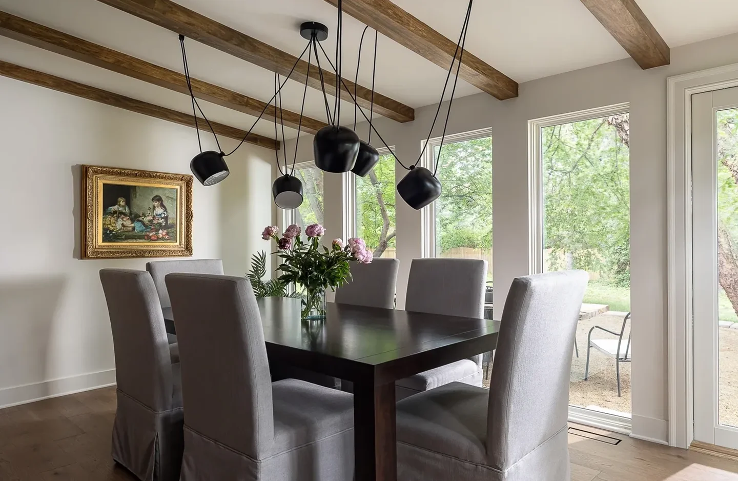 A dining room table with chairs and lights hanging from the ceiling.