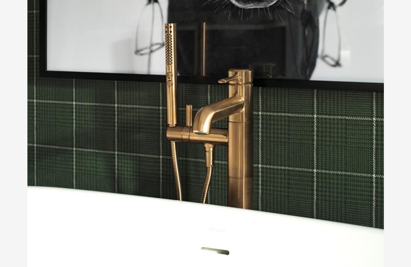 A bathroom with green tile and gold fixtures.