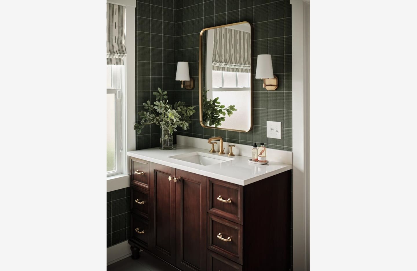 A bathroom with green walls and dark wood cabinets.