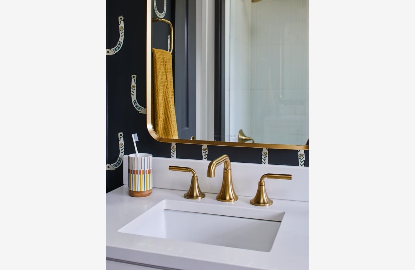 A bathroom sink with gold faucets and a mirror.