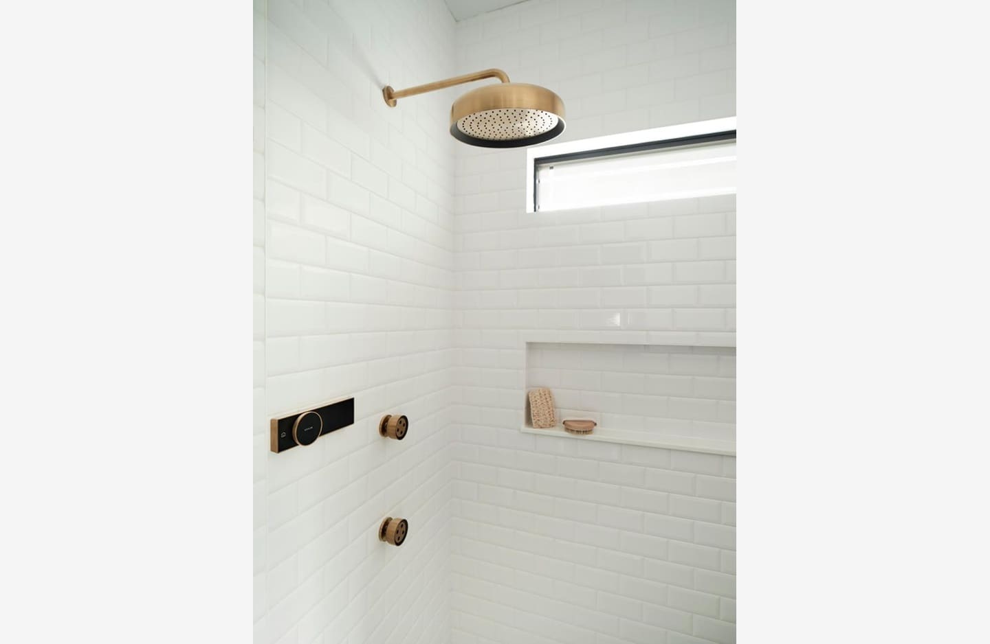 A bathroom with white walls and a wooden shower head.