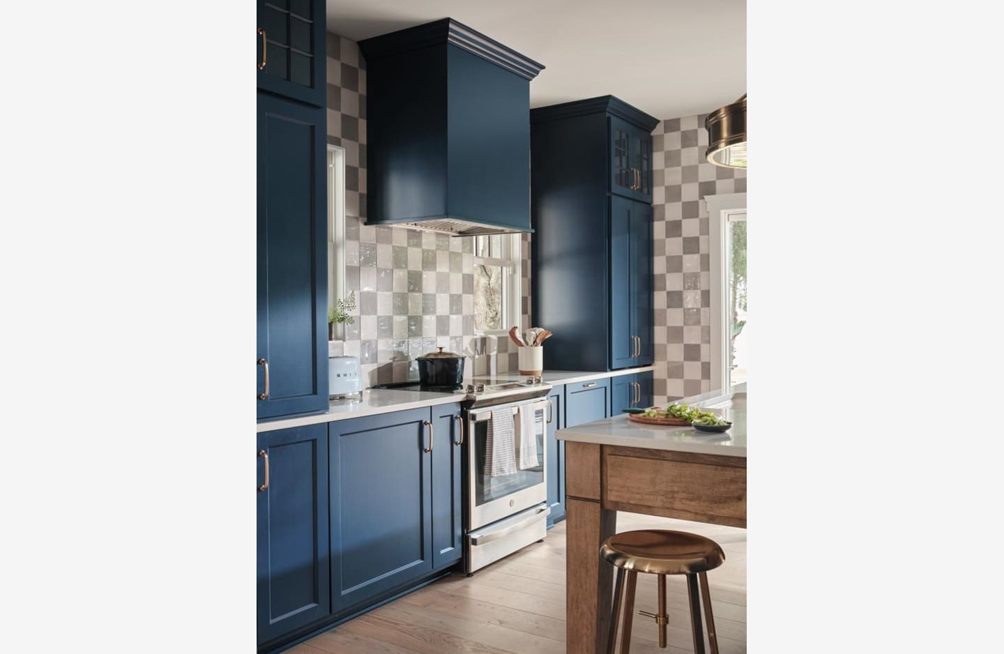 A kitchen with blue cabinets and checkered walls.